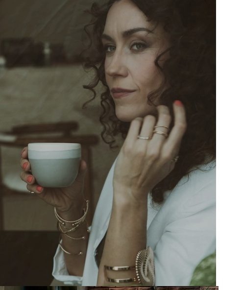 Moody portrait of a woman with curly hair holding a cup of Arabic coffee
